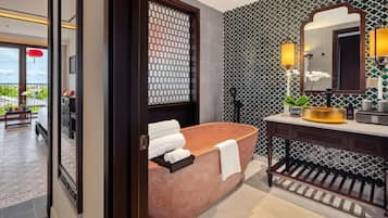 A modern bathroom with a freestanding bathtub, a vanity with a mirror, and a patterned wall.