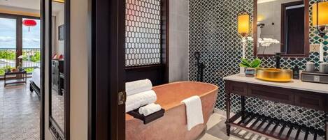 A modern bathroom with a freestanding bathtub, a vanity with a mirror, and a patterned wall.