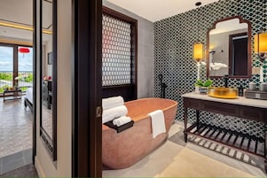 Un baño moderno con una bañera independiente, un tocador con espejo y una pared con diseño.