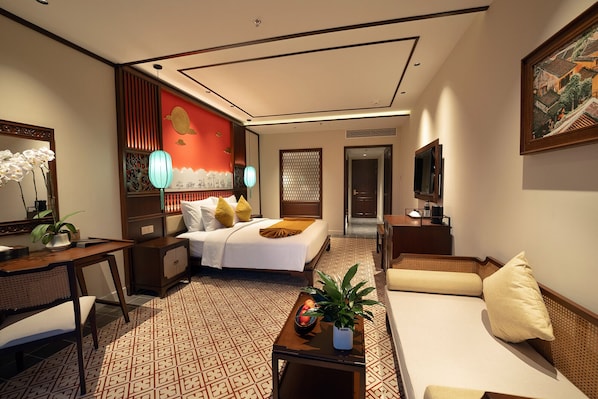 A hotel room with a bed, a sofa, a desk, a TV, and a large window.