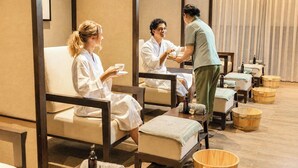 Un cuarto de spa con asientos individuales, tinas de madera y una persona atendiendo a los huéspedes.
