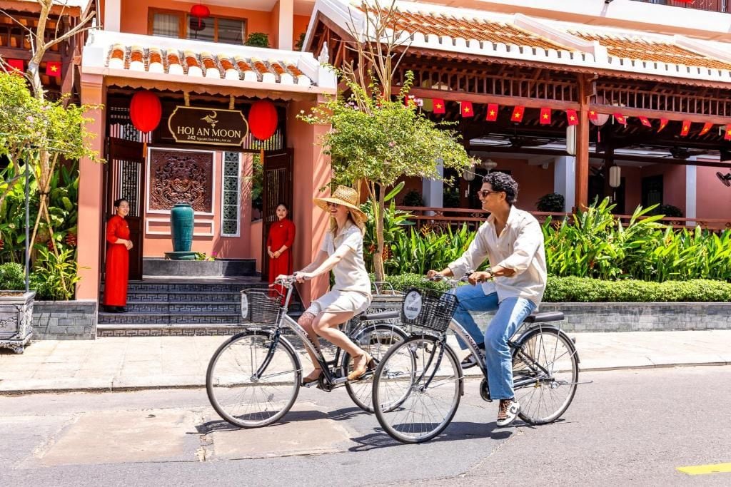 A street scene with a restaurant named 'Hoi An Moon' and two people riding bicycles.