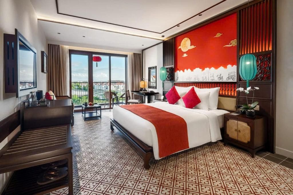 A hotel room with a large bed, a desk, a chair, and a view of the outdoors.