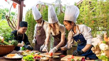 A group of chefs preparing food outdoors with a variety of vegetables and a wooden table.