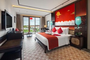 A hotel room with a bed, a desk, a TV, a balcony, and a view of the city.