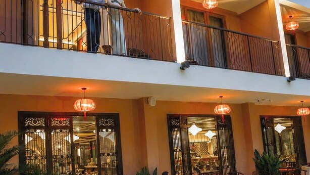 Un hotel con piscina, zona de estar exterior y restaurante.