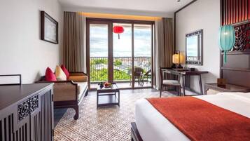 Quarto de hotel com cama, escrivaninha, cadeira e vista para o exterior.