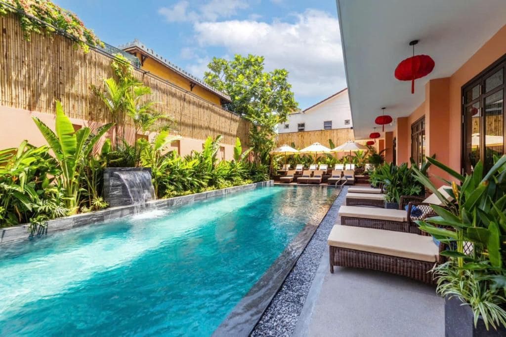 A swimming pool with lounge chairs and a waterfall feature.