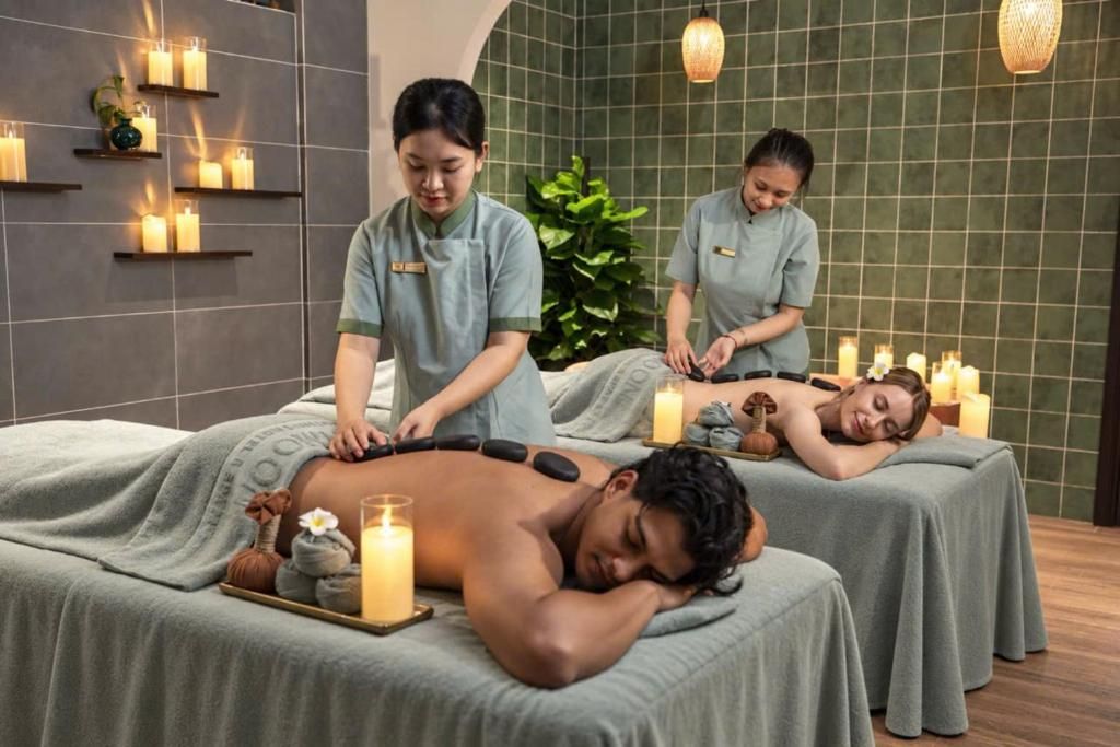 Un ambiente de spa con dos camillas de masaje, velas y una pared verde.
