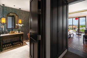 Un baño moderno con puerta de madera oscura, espejo y tocador con lavamanos y perchero para toallas.