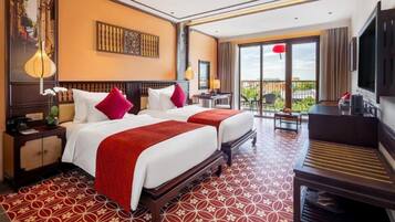 Quarto de hotel com duas camas, uma escrivaninha, televisão e varanda com vista.