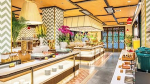 Montaje de bufé con diferentes estaciones de comida, una lámpara colgante grande y plantas decorativas.