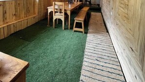 A room with wooden walls, a green carpet, and a bench along one wall. - Peach Farm Stay (Ramgarh)