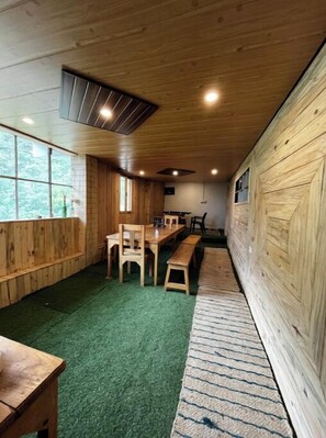 A room with wooden walls, a green carpet, and a bench along one wall. - Peach Farm Stay (Ramgarh)