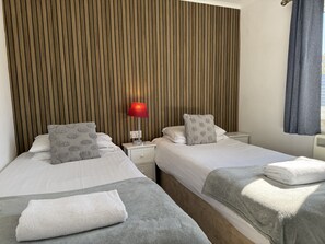Una habitación de hotel con dos camas, una lámpara roja y un panel de pared de madera.