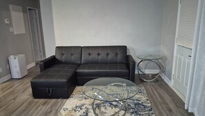 A living room with a sectional sofa, a glass coffee table, and a small side table.