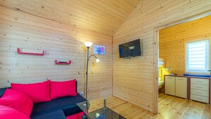 A cozy cabin interior with a sofa, a glass coffee table, a TV, and a kitchenette. - Amazing home in Wicie with WiFi (Wicie)
