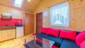 A cozy cabin interior with a kitchenette, a glass coffee table, and a red sofa. - Amazing home in Wicie with WiFi (Wicie)