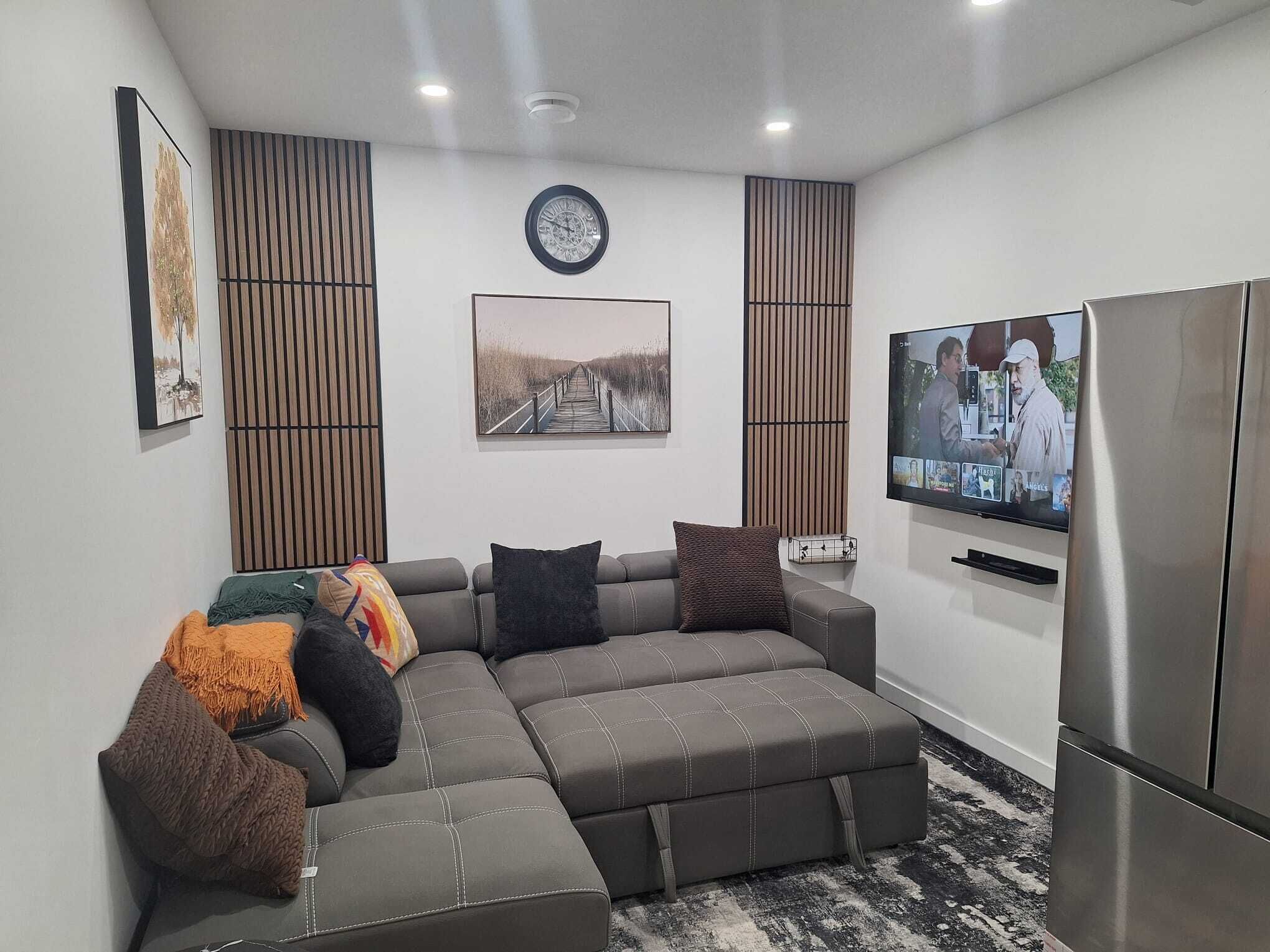 A modern living room with a sectional sofa, a flat-screen TV, and a built-in refrigerator.