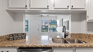 A kitchen with granite countertops, stainless steel appliances, and white cabinetry.