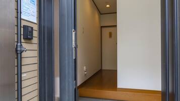 A hallway with a door leading to a room, a light fixture on the ceiling, and a sign on the wall.