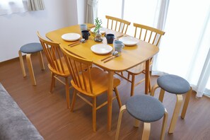 A dining table set with plates, cups, and cutlery, surrounded by wooden chairs with grey cushions. - 3-Bedroom House, Near Ikebukuro and a Shopping Arcade (Nukui, Nerima City)