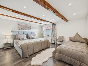 Ein Schlafzimmer mit Bett, Stuhl, Fenster und Deckenbalken.