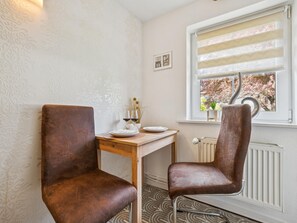 Ein Essbereich mit zwei Stühlen, einem Tisch und einem Fenster mit Jalousien.