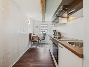 Eine kleine Küche mit Holzauskauf, einem eingebauten Backofen und einer Edelstahl-Spüle.