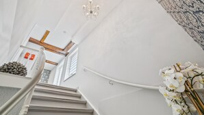 Una escalera con un candelabro, un papel tapiz decorado y un arreglo floral.