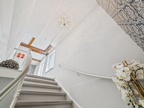 Eine Treppe mit einem Chandelier, einer Wand mit Muster und einer Blumenkomposition.