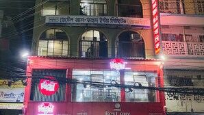 A multi-story building with a fitness club on the ground floor, a pharmacy on the second floor, and a brightly lit shop with a neon sign on the ground floor. - HOTEL Al-FAHAD INT.LTD. (Dhaka)