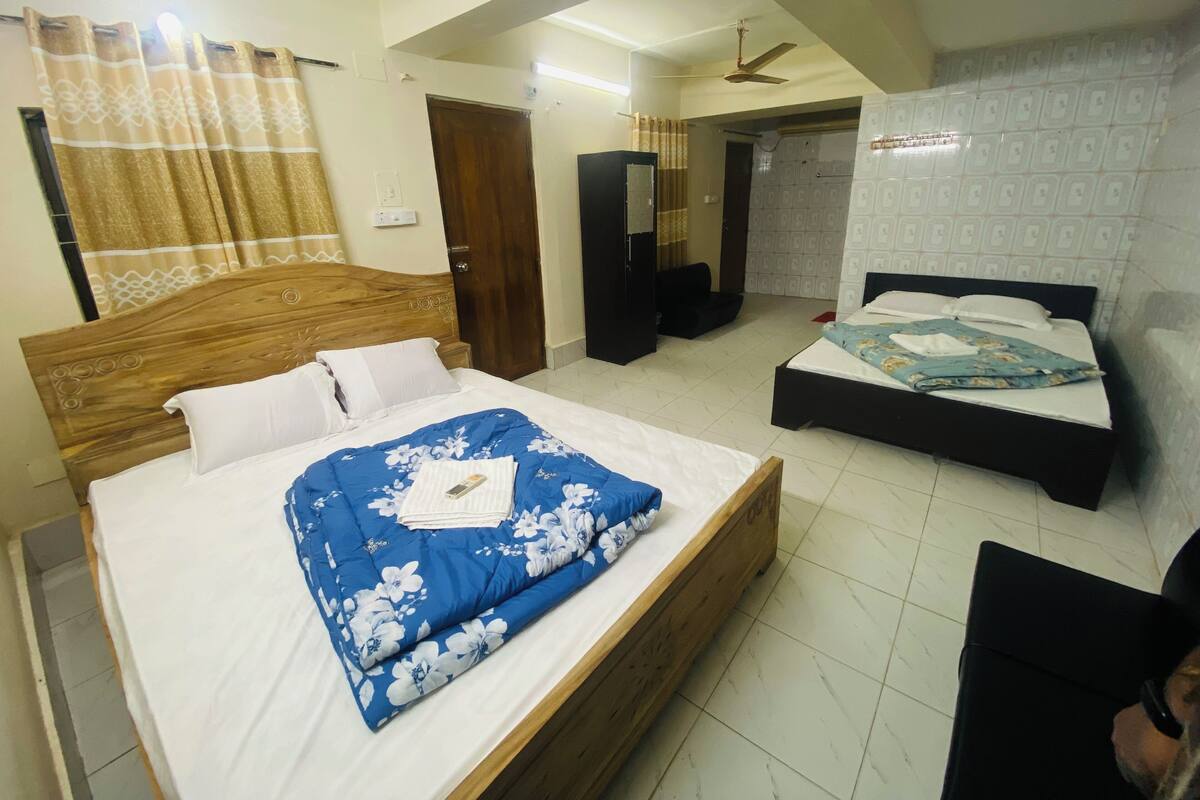A bedroom with two beds, a ceiling fan, a wardrobe, and a mirror.