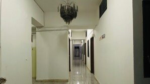 A long, narrow hallway with a chandelier, white walls, and a tiled floor. - HOTEL Al-FAHAD INT.LTD. (Dhaka)