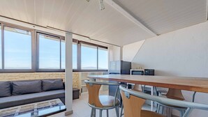 Cozinha moderna com mesa de madeira e banquetas, sofá e parede de pedra.