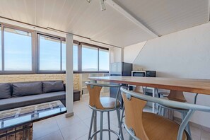 A modern kitchen with a wooden table and bar stools, a sofa, and a stone wall.