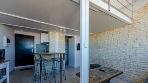 Uma cozinha moderna com área de refeições, parede de pedra e um pequeno espaço para sentar.