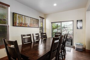 Ein Esszimmer mit Holztisch und -stühlen, einem großen Gemälde an der Wand und Blick durch eine Glastür.