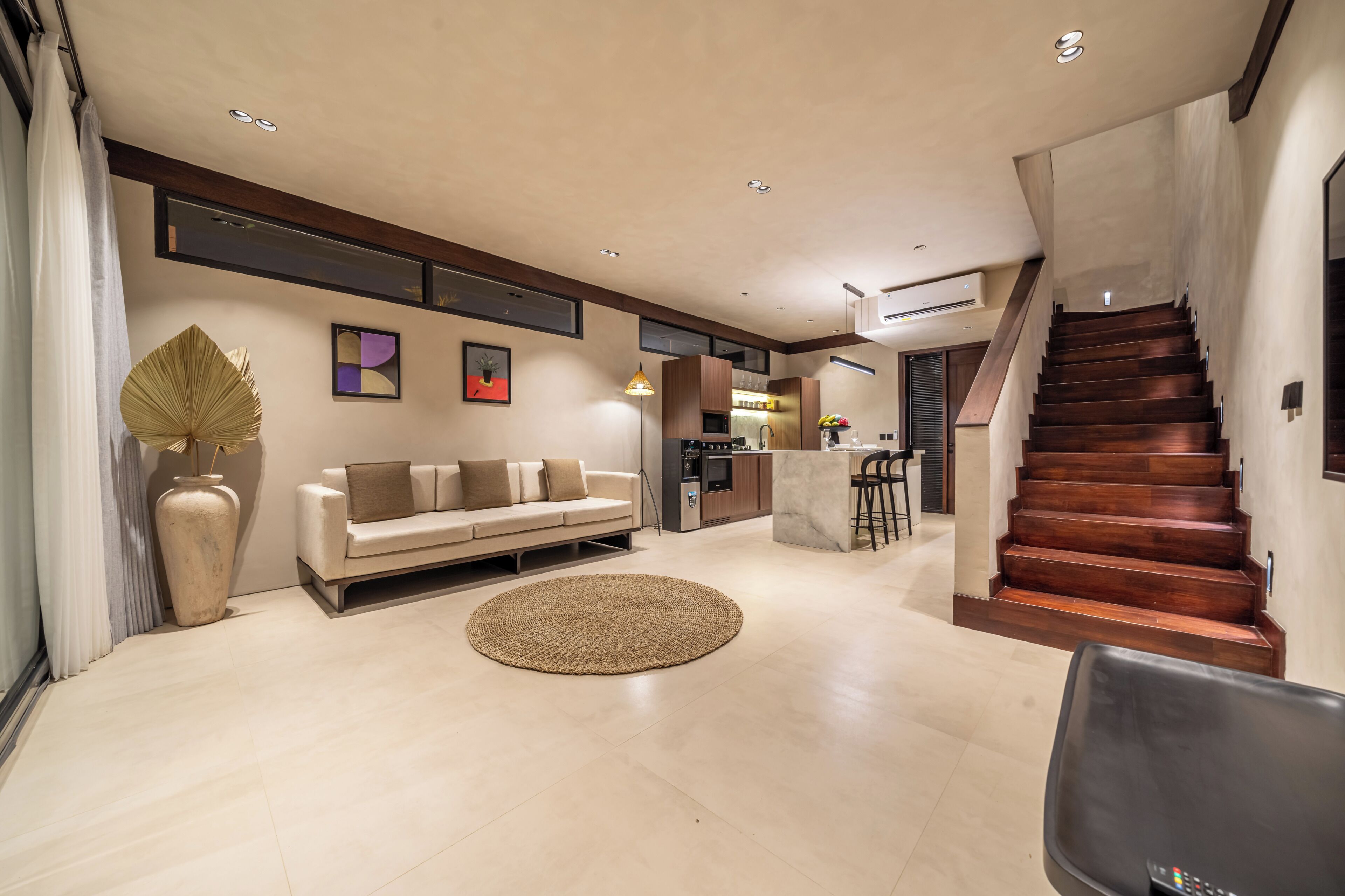 A modern living room with a sofa, a coffee table, and a staircase leading to an upper level.