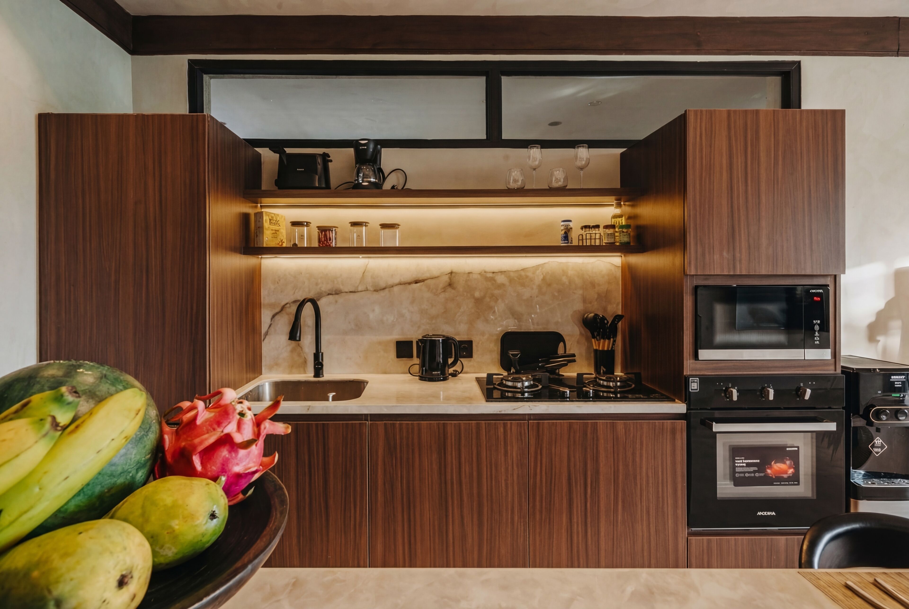 Una cocina moderna con armarios de madera, encimera de mármol, un lavabo, una estufa, un horno y un microondas.