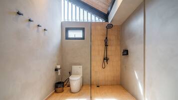 A modern bathroom with a toilet, shower, and a small window.
