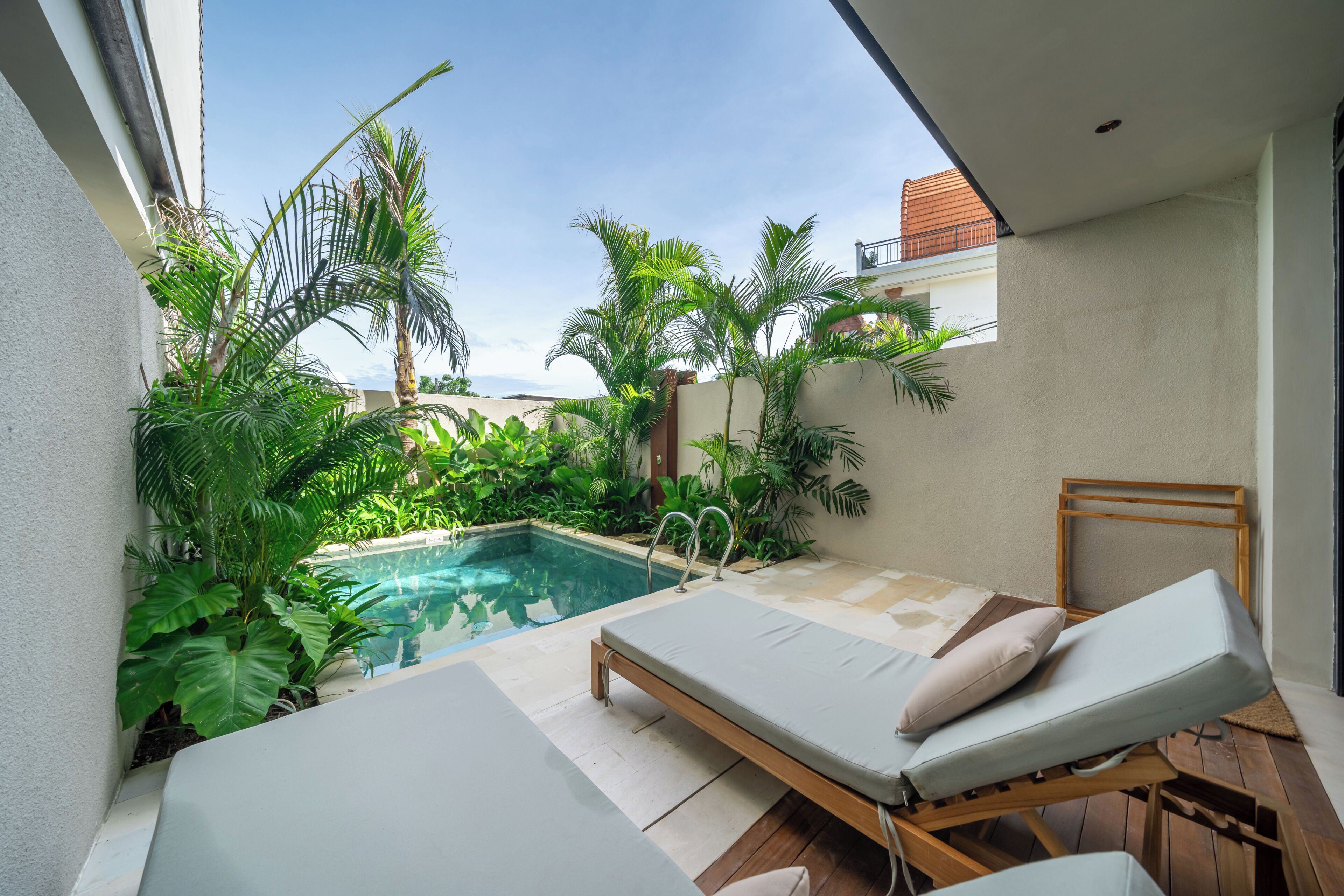 A poolside area with lounge chairs, a small pool, and lush greenery.