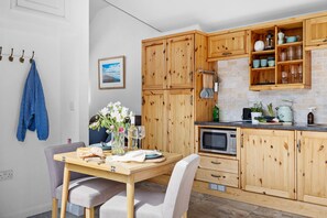Eine Küche mit Holzschränken, einer Mikrowelle und einem Essbereich mit Tisch und Stühlen.