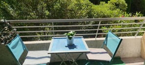 Ein Balkon mit Tisch, Stühlen, einer Topfpflanze und einem Geländer.