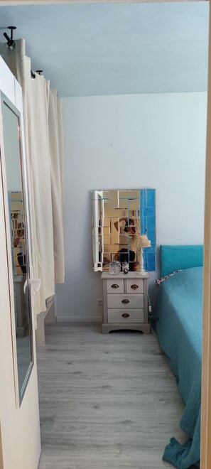 Ein Schlafzimmer mit Bett, Kommode mit Spiegel und Kleiderschrank.