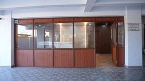 Entrada de hotel con fachada de madera, amplios ventanales de vidrio y suelo de baldosas.