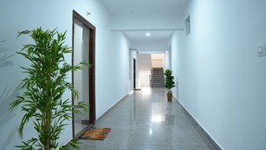 Un pasillo con piso pulido, una puerta a la izquierda y una escalera al final.