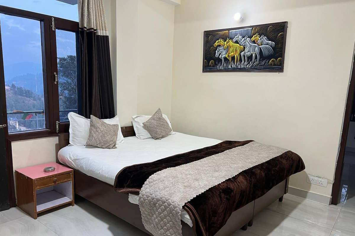 A bedroom with a bed, pillows, a nightstand, a painting, and a window with curtains.