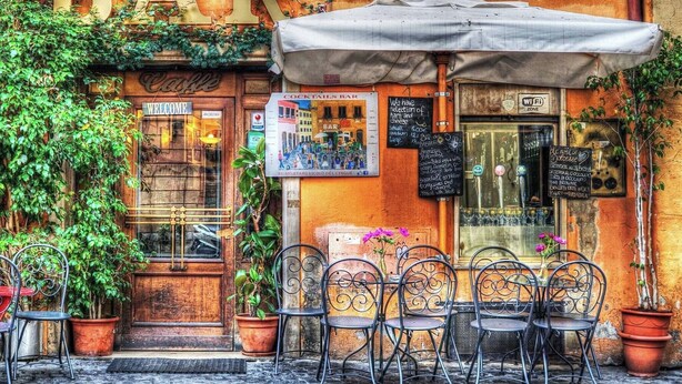 A bar with outdoor seating, a signboard, and a chalkboard menu. - Captivating Loft in Prime Location near Colosseum (Roma)