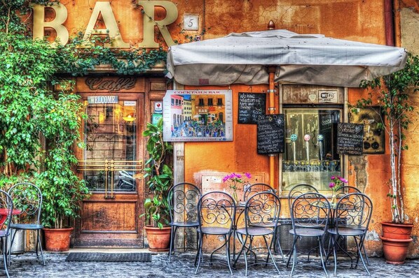 A bar with outdoor seating, a signboard, and a chalkboard menu. - Captivating Loft in Prime Location near Colosseum (Roma)